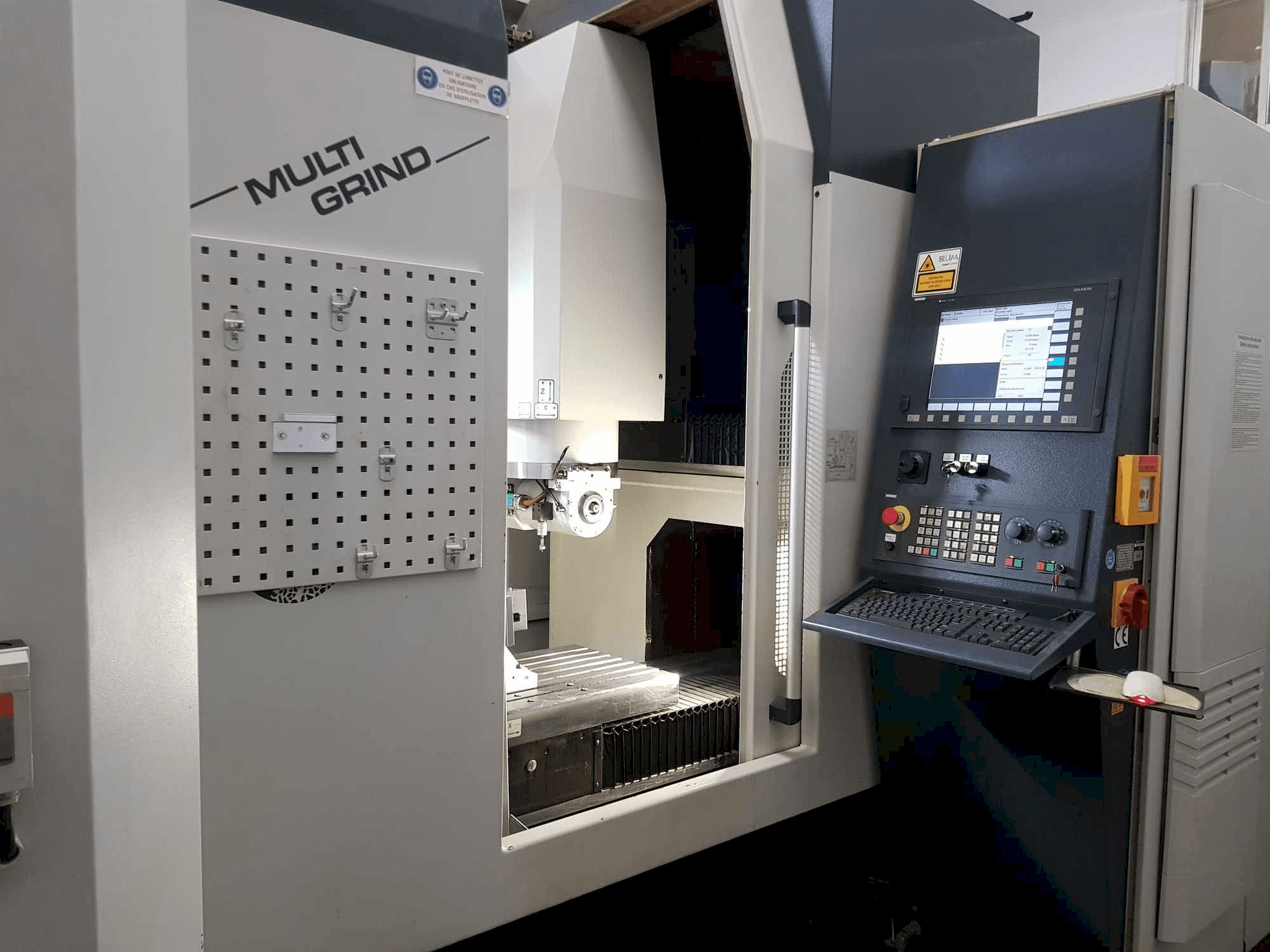 Stroj Multi Grind CNC s pohledem zepředu, s ovládacím panelem, odkládací deskou a otevřeným pracovním prostorem.